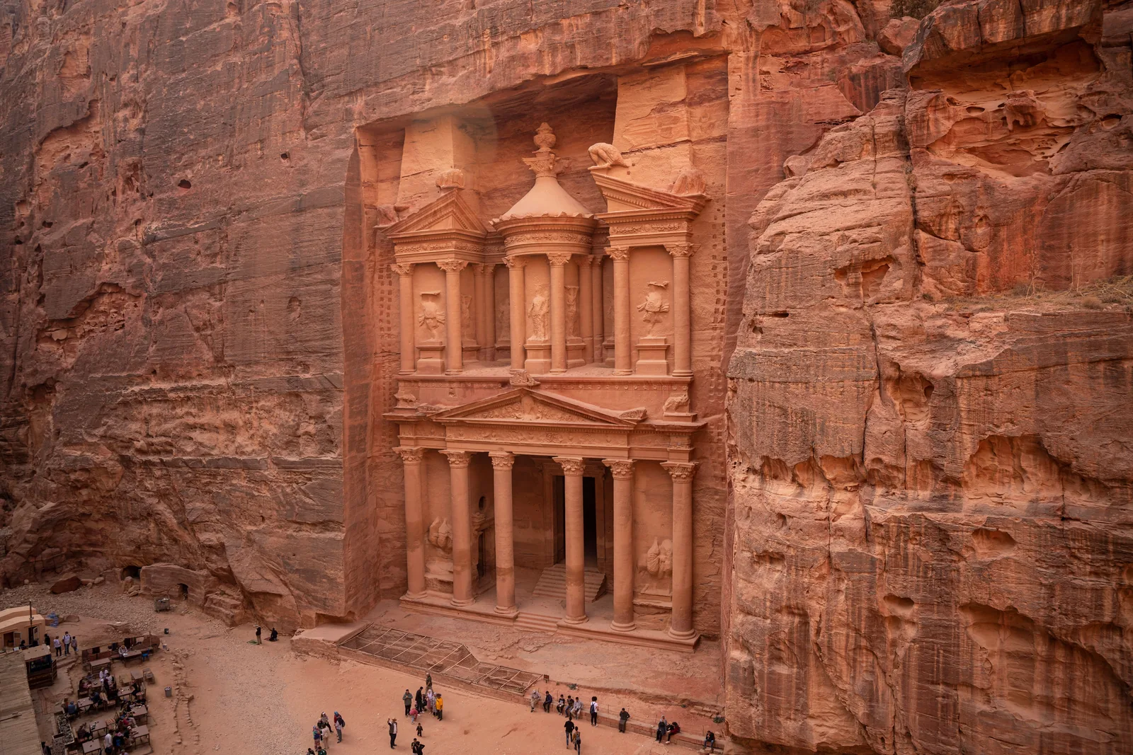 The Treasury at Petra carved into sandstone cliffs, with visitors in front