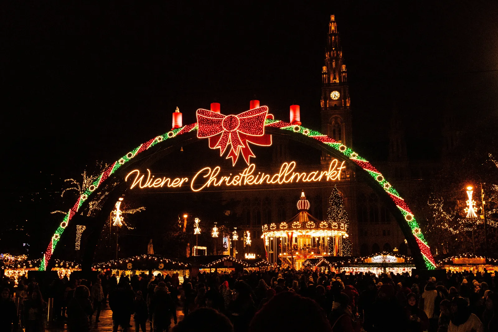 Illuminated entrance arch of the Wiener Christkindlmarkt in front of Vienna City Hall at night