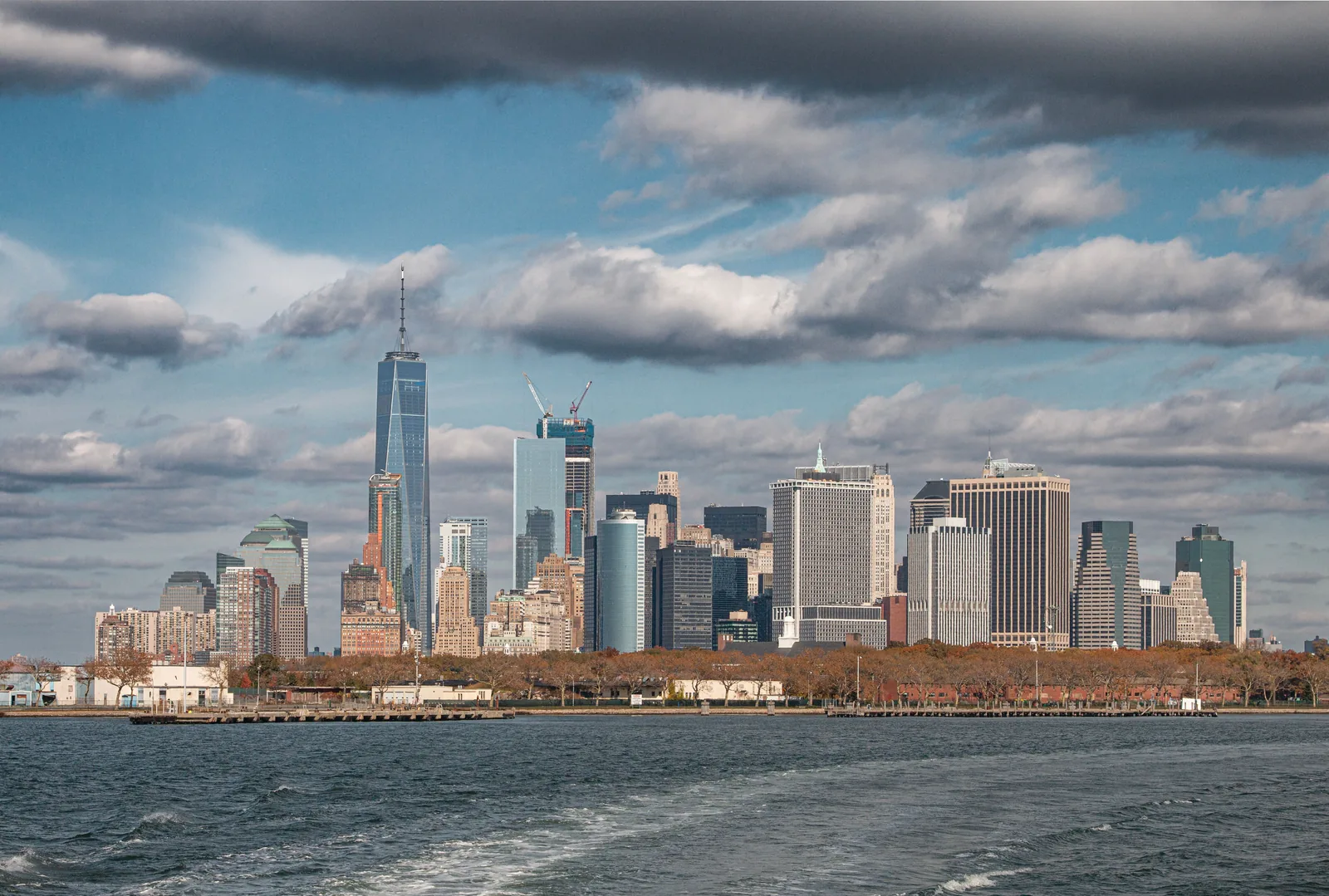 Lower Manhattan skyline behind autumn trees, seen from the water