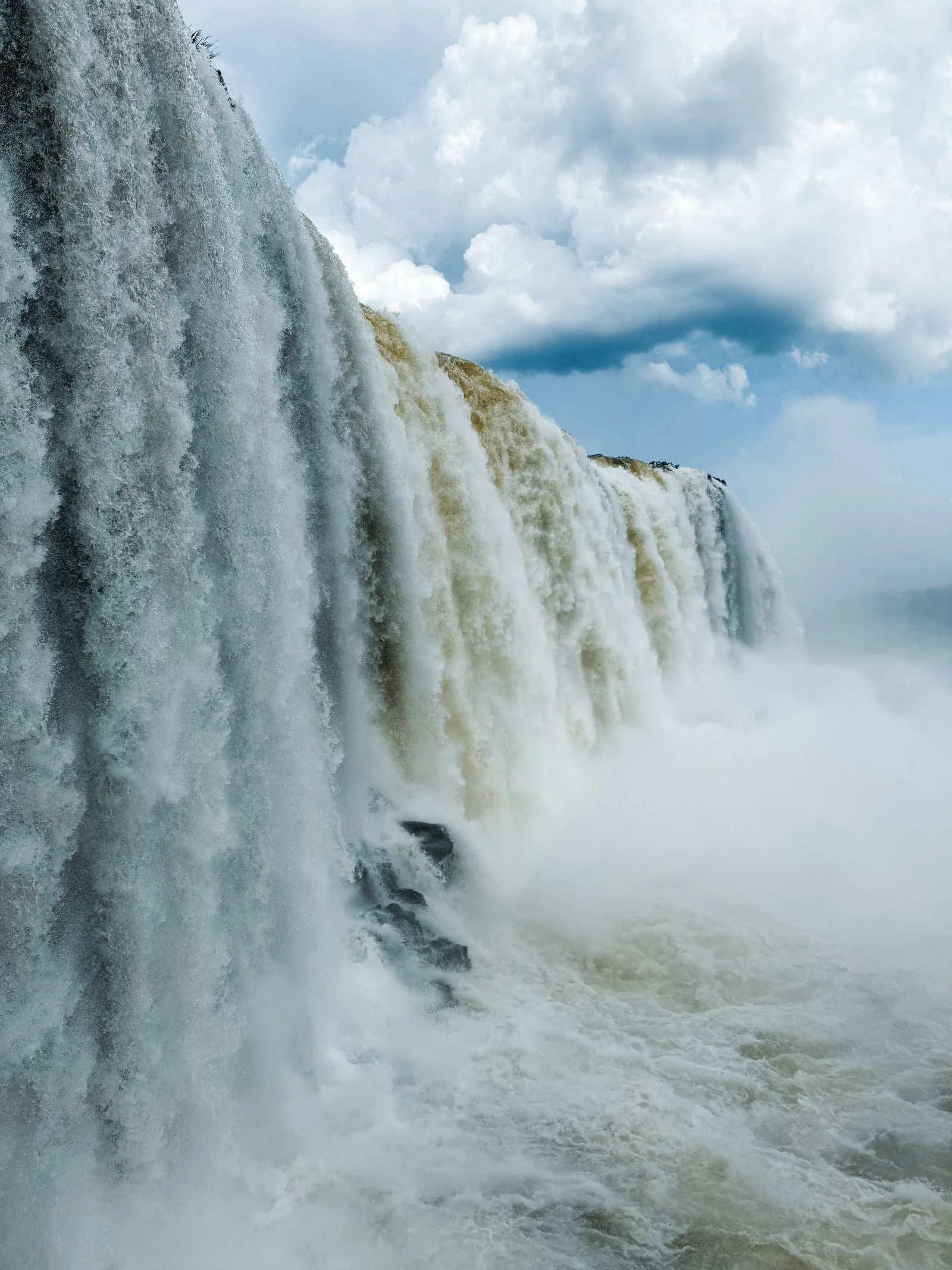 Water pouring into the Devil's Throat at Iguazú Falls under dramatic clouds