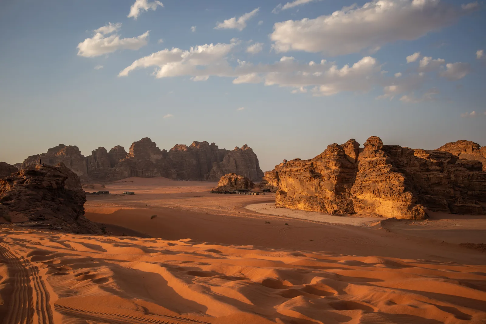 Golden-hour light over red sand and sandstone mountains in Wadi Rum, Jordan