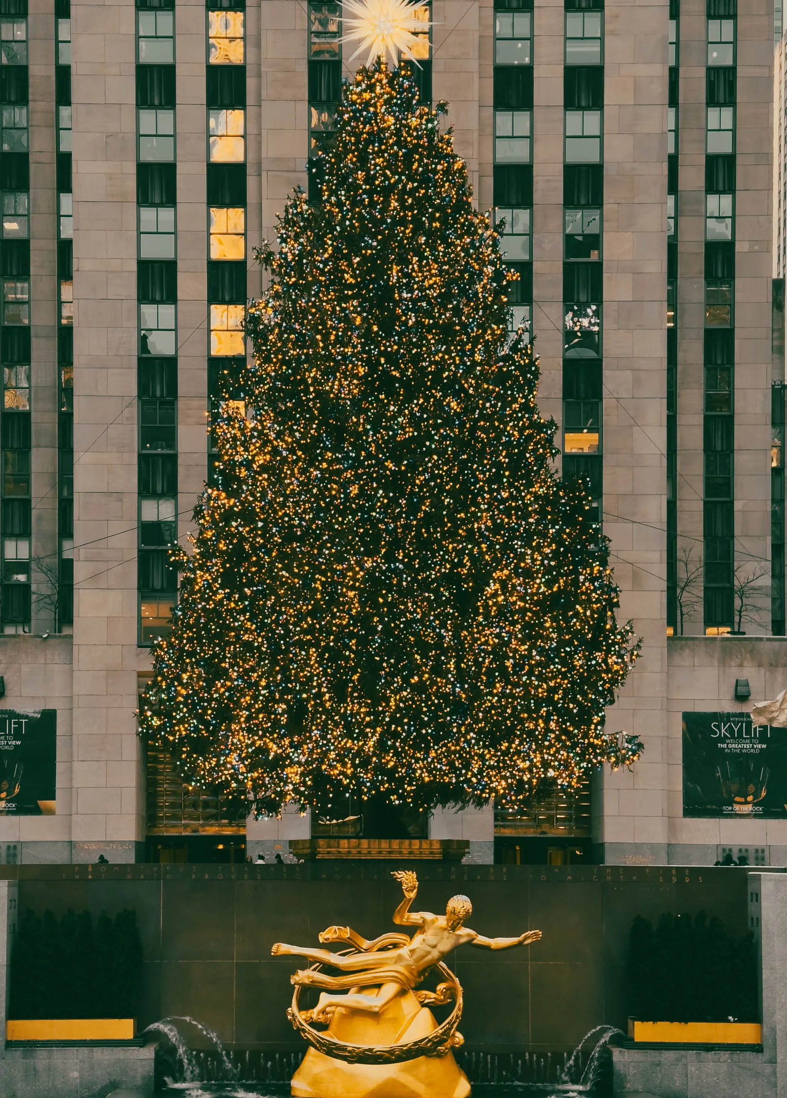 The Rockefeller Center Christmas tree lit with thousands of lights above the golden Prometheus statue