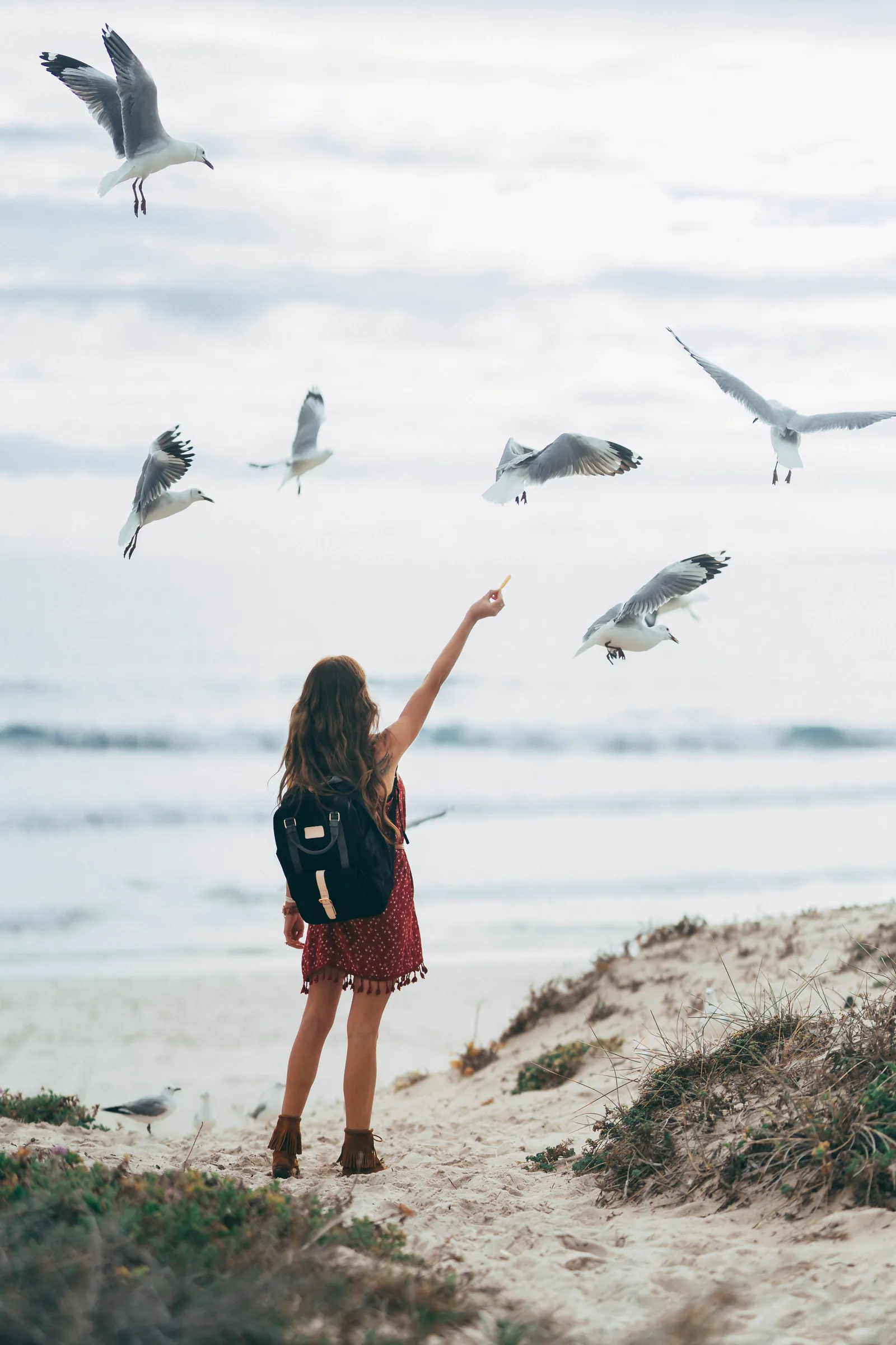 Traveler on a windy Cape Town beach with mountains beyond the bay